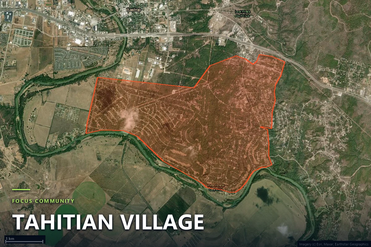 Satellite view of the Tahitian Village boundary south of the Colorado River in Bastrop County, Texas, showing the subdivision's curling street network cut through pine timber with many undeveloped wooded lots between houses