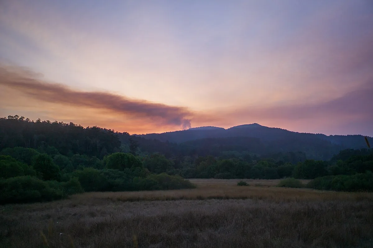 Woodward Fire (2020) in Marin County, California - Smoke rises from a forested ridge in the distance into a partly cloudy sky. Marin County and the San Francisco Bay Area experience
