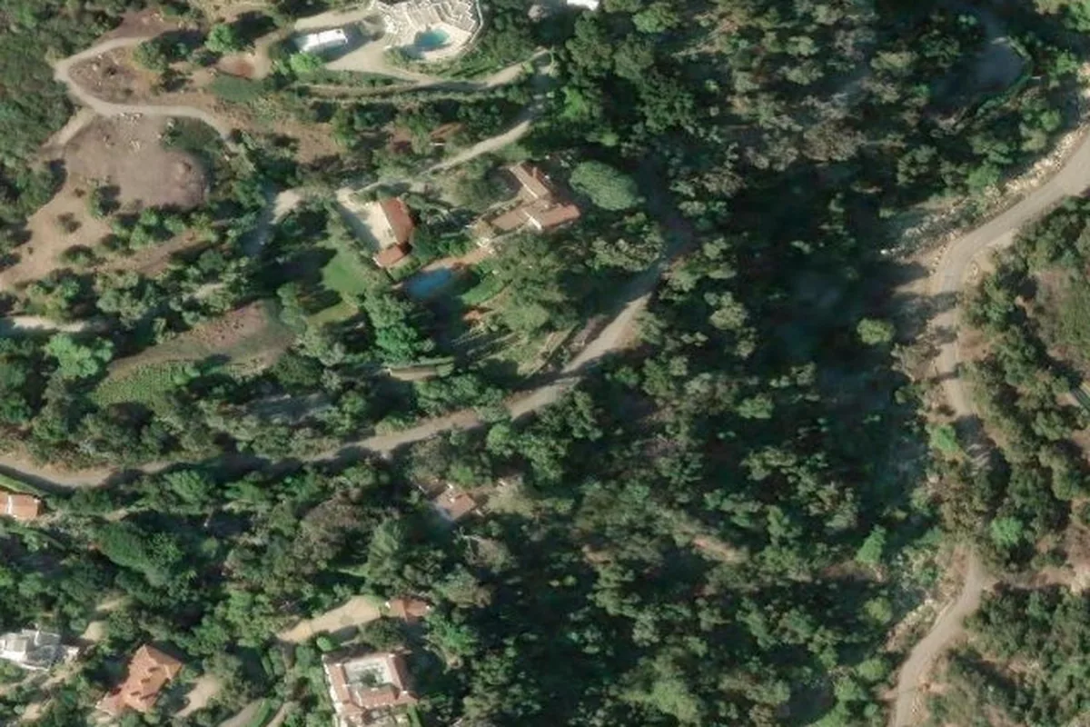 High-resolution satellite imagery of an East Mountain Drive estate in Montecito, showing a home set among dense mature trees on a canyon bench below the Santa Ynez Mountains