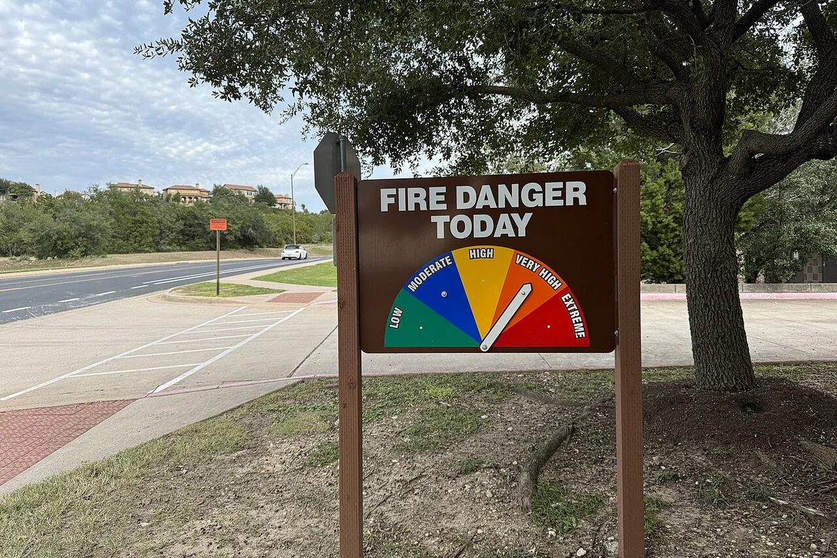 A fire danger rating sign standing in dry grass and scrub on the outskirts of Austin, Texas, in November 2023